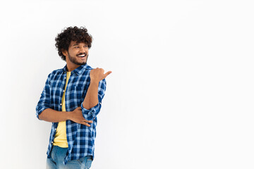 Young Asian man with curly hair and casual stylish clothes smiling with his finger pointing on a...