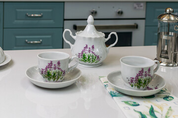 white with lilac flowers tea set on a white table