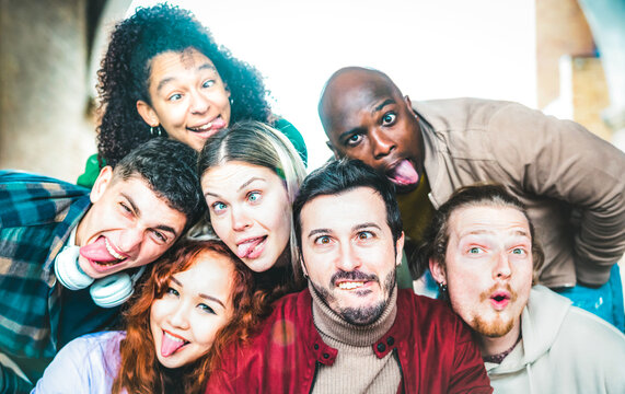Multicultural guys and girls taking funny selfie out side - Happy life style concept by young multiethnic friends having fun together - Bright vivid backlight filter - Focus on mid mustache guy