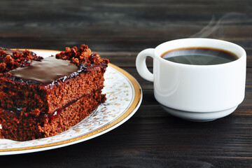 A piece of Chocolate cake on a plate and cup of black coffee on a wooden background.Slice of Homemade brownie cake.Copy space