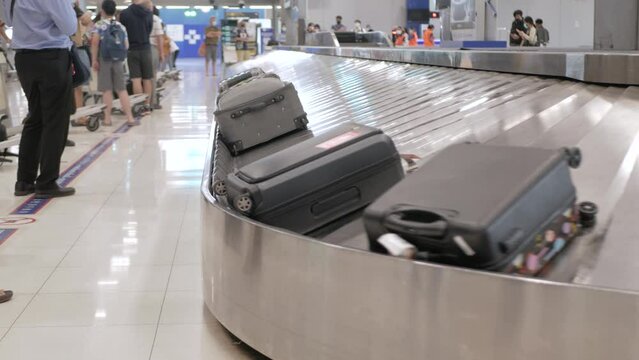 View of airport luggage conveyor belt. luggage on the baggage claim belt. People come from airplane, waiting and picking their bags and cases