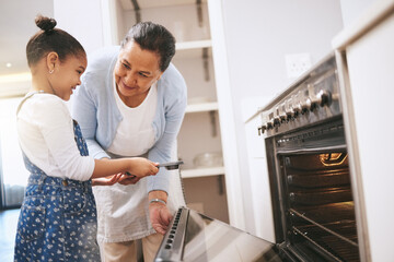 Dont get too close. Shot of a mature woman helping her grandchild safely open the oven at home.