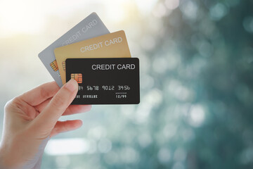 Woman hand holding various credit cards on natural bokeh background.
