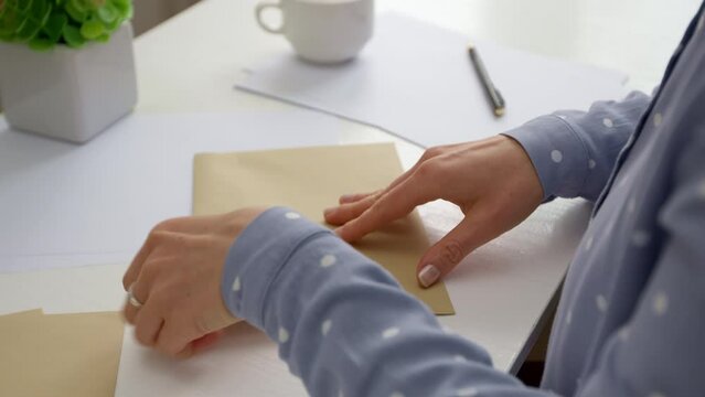 The woman puts the letter in an envelope and signs the address.