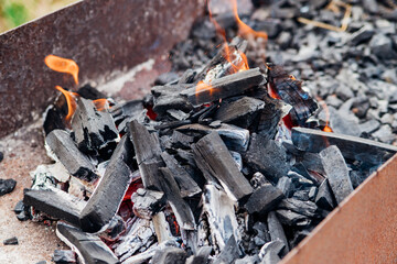 A brightly burning bonfire with a red flame made from wood in an outdoor grill.An adventurous lifestyle in travel. Active weekend recreation in the wild outdoors.