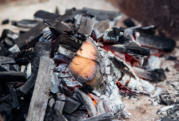 A brightly burning bonfire with a red flame made from wood in an outdoor grill.An adventurous lifestyle in travel. Active weekend recreation in the wild outdoors.