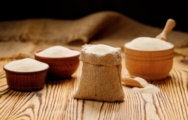 Fototapeta na wymiar Semolina in bowls and bags on a wooden background. High quality photo