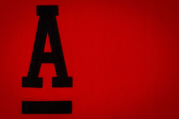 Letter A. Alphabet letter A application and blank label tag made from black material on red fabric background