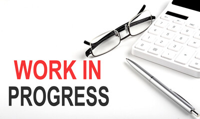 WORK IN PROGRESS Concept. Calculator,pen and glasses on white background