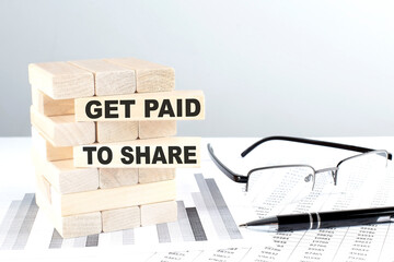 GET PAID TO SHARE is written on wooden blocks on a chart background