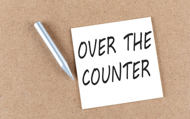 OVER THE COUNTER text on sticky note on a cork board with pencil ,