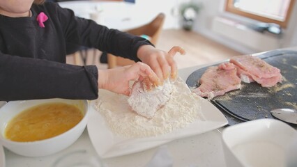 Happy Young Caucasian Girl Learning To Cook Having Time Preparing Meat Chop Batter Coating for...