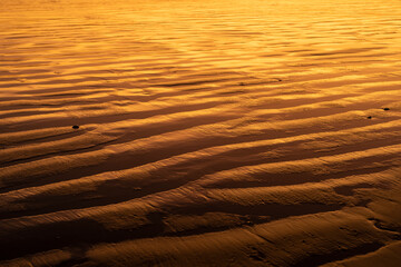 Sand texture waves close up at sunset. Abstract background pattern of sand at the beach.