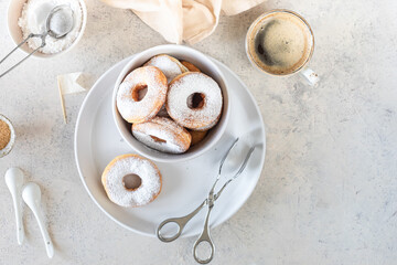 Fototapeta na wymiar Delicious homemade donuts with sugar and a cup of coffee on a white stone background.