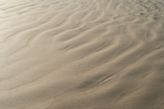 Sand texture waves close up. Abstract background pattern of wet sand beach.