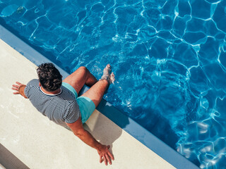 Fashionable man sitting by the pool  on the empty deck of a cruise liner. Closeup, outdoor....