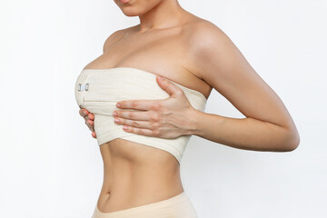 Cropped shot of young fit woman wrapped in elastic bandage after breast augmentation isolated on...