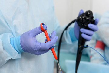 Endoscopic examination.
Instruments for gastroscopy and colonoscopy close-up. The doctor holds a flexible endoscope and biopsy forceps in his hands. Endoscopy and minimally invasive surgery.