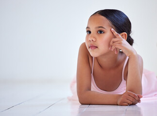 Dreaming about dancing on the big stage. Shot of a little girl looking thoughtful while lying on...