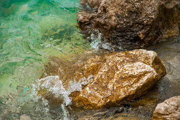 stone beach washes the sea. The sea is clear blue. Background of stone shore by the sea.