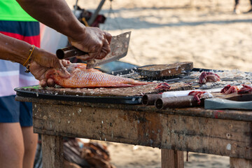 Hands cutting raw fish in rustic table