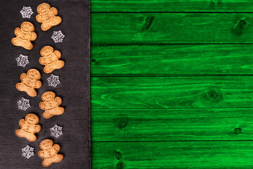 Gingerbread cookies in decoration on a green wooden table, directly above.