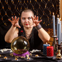 A bald woman fortune-teller is engaged in esotericism in a magic salon.