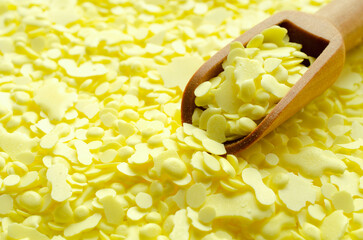 Pile of yellow sulfur granules used in medicine, fertilizers. Wooden spoon on yellow sulfur, top...