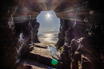 View form insinde the sea cave of uneven form. Loughshinny beach coast on the Ireland coast. Whit sun HDR Europe