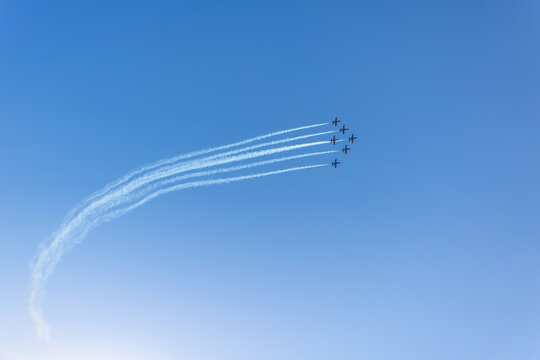 Silhouette of an airplane performing acrobatic flight on blue sky. Trace of smoke behind. - Powered by Adobe