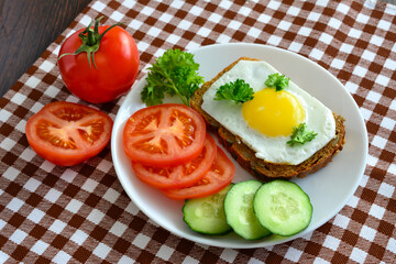 healthy breakfast with wholegrain sandwich with fried egg and tomato and cucumber slices, close-up