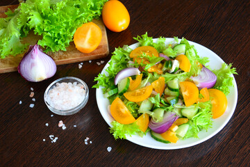 vegetable salad with yellow tomatoes, salad greens and red onion, close-up