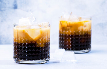 Trendy alcoholic cocktail drink with vodka, coffee liqueur, cream and ice, gray background, bar tools