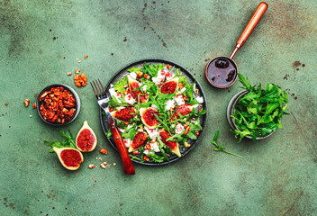 Delicious summer salad with figs, feta cheese, walnuts, arugula and sweet  jam dressing on rusty...