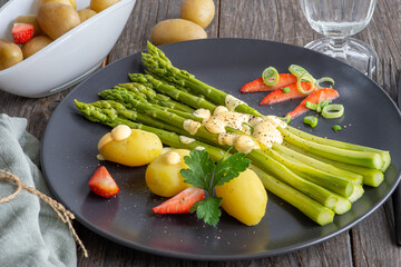 green asparagus, hollandaise sauce and potatoes on a plate, fresh cooked meal