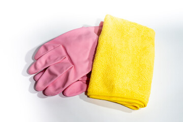 A pair of folded pink rubber cleaning gloves and a yellow microfiber cloth. Set of cleaning accessories isolated on white background.