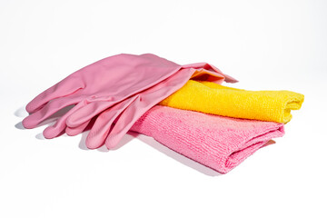 A pair of pink folded rubber cleaning gloves and microfiber rags. Set of cleaning accessories isolated on white background.