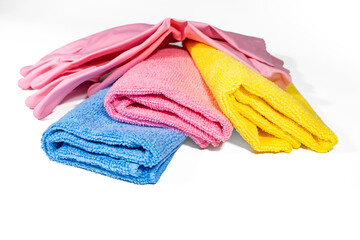 A pair of new folded rubber cleaning gloves and three multicolored microfiber rags. Set of cleaning accessories isolated on white background.