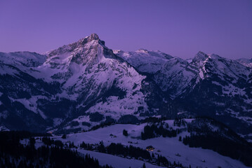 Morgendämmerung über den Bergen der winterlich verschneiten Glarner Alpen in der Schweiz