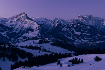 Morgendämmerung über den Bergen der winterlich verschneiten Glarner Alpen in der Schweiz