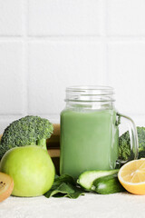 fresh green smoothie in glass bottle with vegetables on white ceramic tile background.vegan food, self care and healthy lifestyle.Healthy detox diet