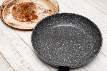 Comparison of pans. Old and new frying pan. New and old damaged non-stick coating.