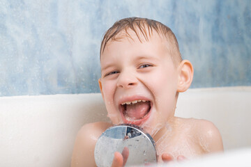 A young boy takes a bath. Played with a shower. The joy, pleasure of bathing.