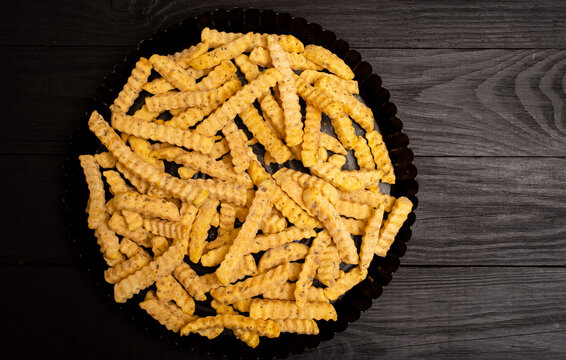 Frozen fries with spices on a black background. Preparation for cooking.