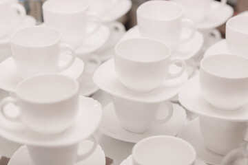 a lot of rows of pure white cups with plates for coffee or tea break . High quality photo