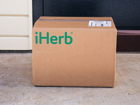 Tambov, Russian Federation - February 05, 2022 An iHerb cardboard box delivered to the house door. Close-up