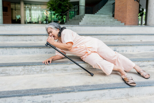 Asian elderly woman patient slipping, falling while walking down the stairs, she is a patient of osteoarthritis and osteoporosis, to people health care and osteoarthritis concept.