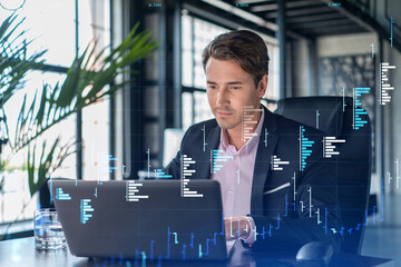 Handsome businessman in suit at workplace working with laptop to optimize trading strategy at corporate finance fund. Forex chart hologram over office background