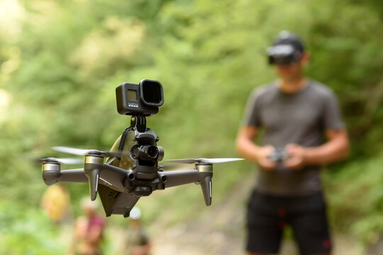 СARPATHIANS, UKRAINE - June, 2021: 
DJI FPV with a top-mounted GoPro HERO8 action camera in flight. A pilot in FPV goggles with a remote control controls a racing high-speed quadcopter in outdoors.