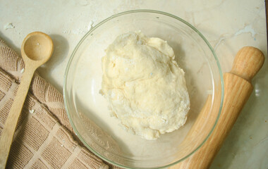 dough for baking, wood spoon and rolling spin, kitchen towel on a kitchen top 